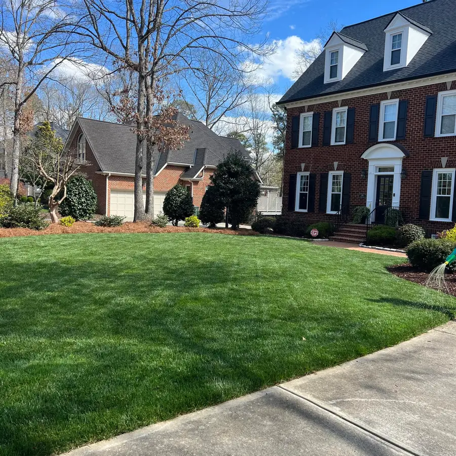 Thick green lawn in front of a brick colonial home